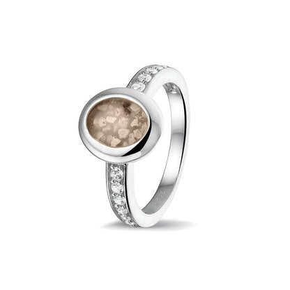 Gedenksieraad, ring 3 mm waar aan de ovale bovenzijde zichtbaar as of haar verwerkt wordt. In de bovenste helft van de ringband zijn zirkonia's of diamanten naar keuze gezet. Transparent