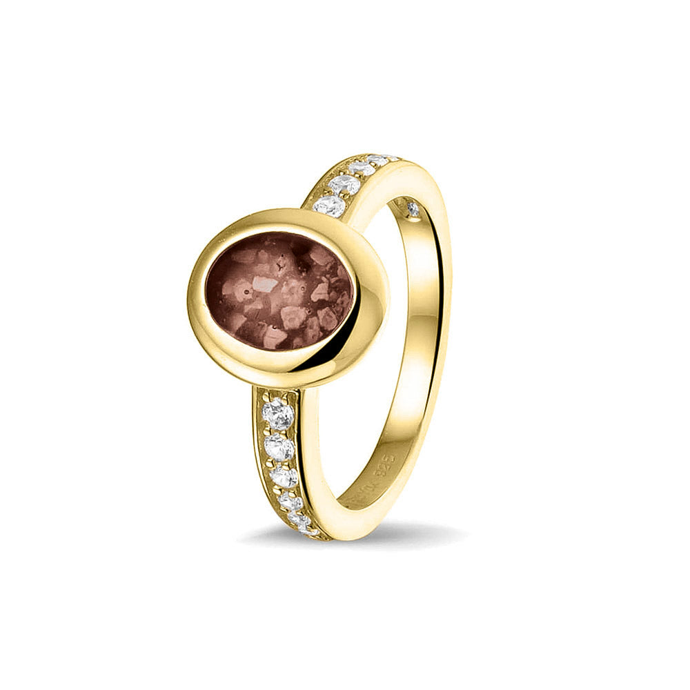 Gedenksieraad, ring 3 mm waar aan de ovale bovenzijde zichtbaar as of haar verwerkt wordt. In de bovenste helft van de ringband zijn zirkonia's of diamanten naar keuze gezet. Brown