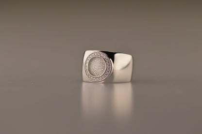 Ring met rond vlak aan de bovenzijde voorzien van een vingerafdruk afgewerkt aan de randen met diamanten. alle