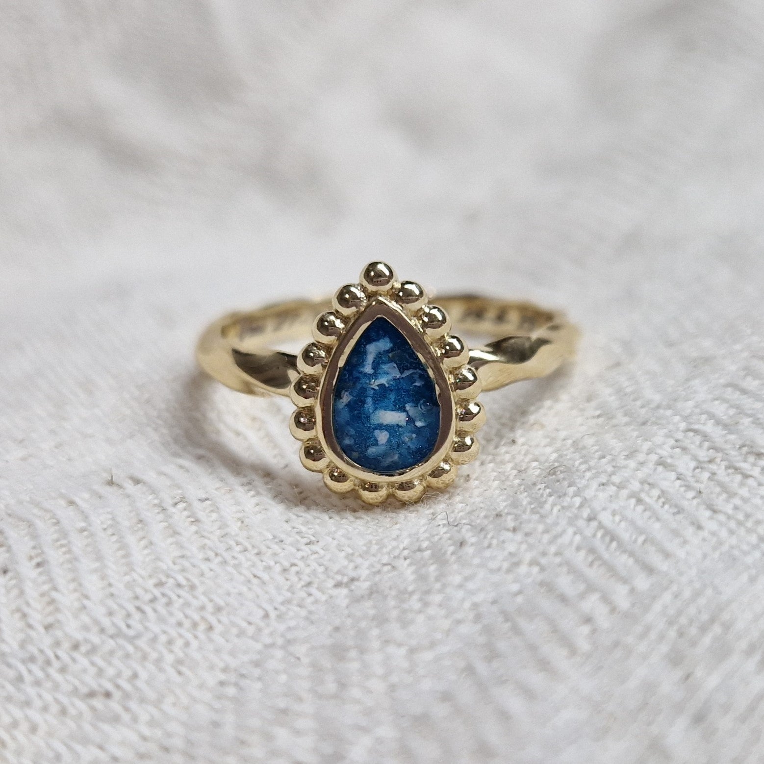 Gedenksieraad, asring met gedraaide scheen waar aan de bovenzijde in druppelvorm met parelrand zichtbaar as of haar (of eventueel melktandjes of moedermelk) verwerkt wordt.alle