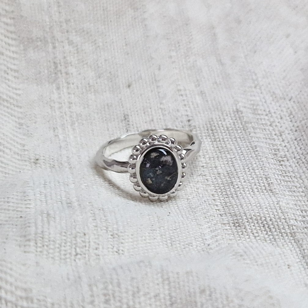 Gedenksieraad, asring met gedraaide scheen waar aan de bovenzijde in ovaalvorm met parelrand zichtbaar as of haar (of eventueel melktandjes of moedermelk) verwerkt wordt. Alle