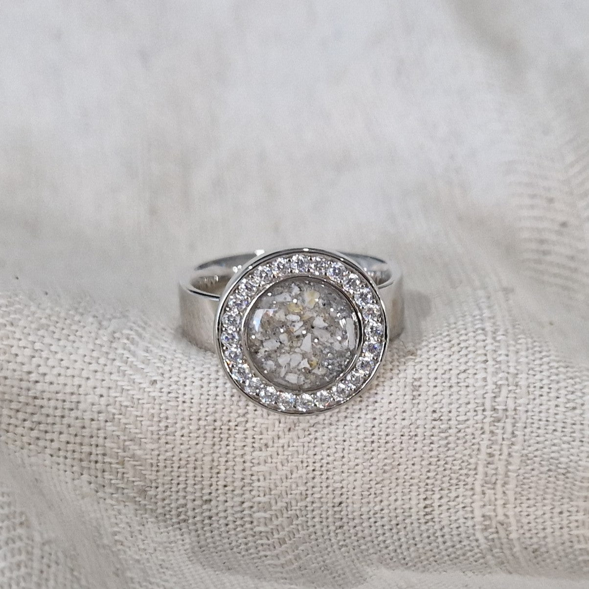 Asring 6 mm uit onze serie gedenksieraden, waar aan de bovenzijde zichtbaar as of haar verwerkt wordt in een rondje, rondom gezet met zirkonia's of diamanten naar keuze. Alle