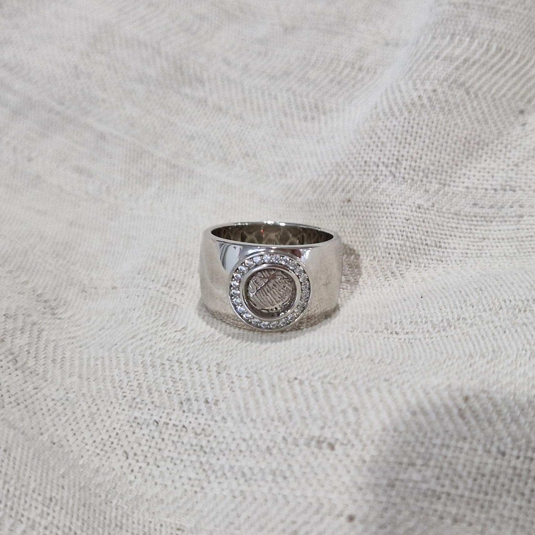 Ring met rond vlak aan de bovenzijde voorzien van een vingerafdruk afgewerkt aan de randen met diamanten. alle