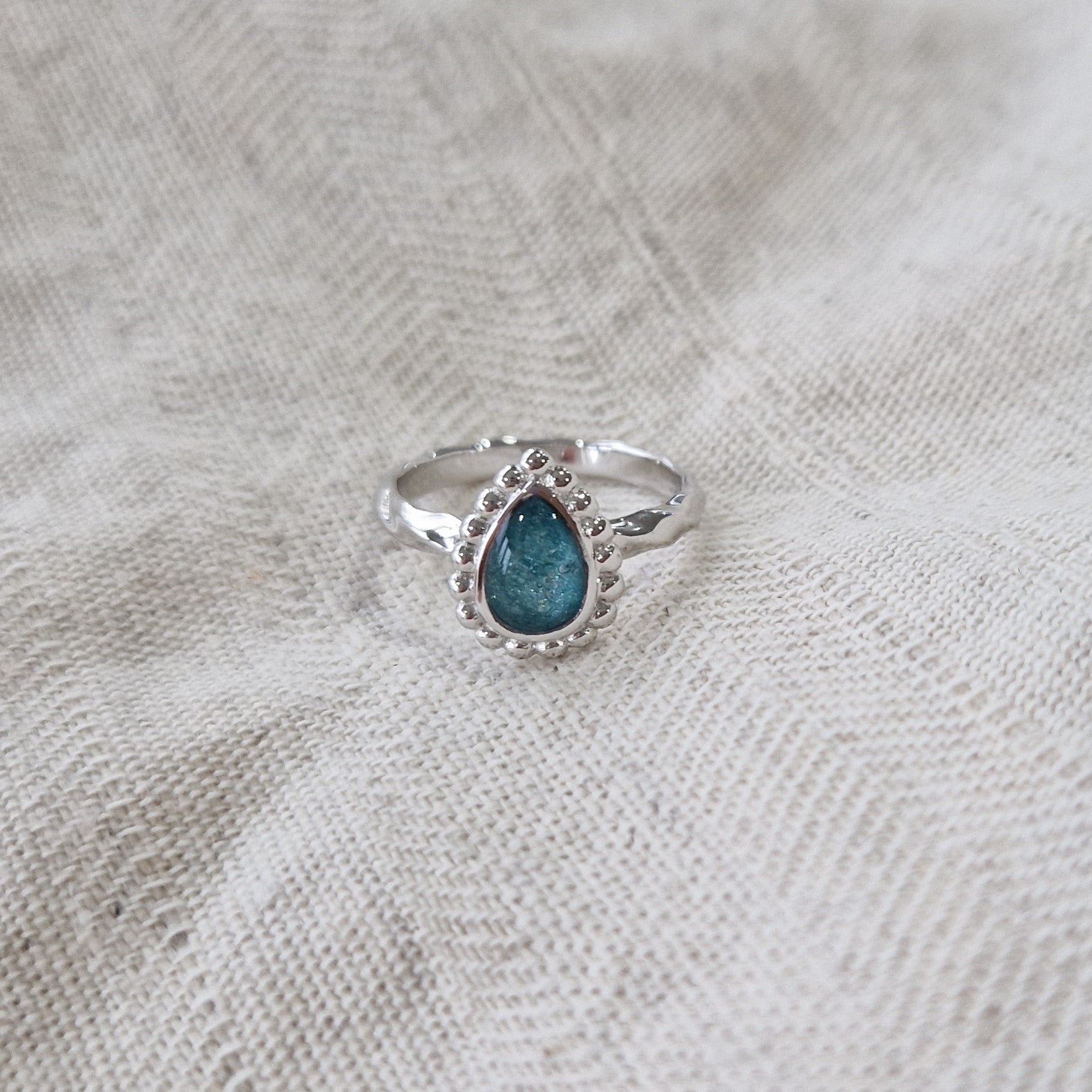 Gedenksieraad, asring met gedraaide scheen waar aan de bovenzijde in druppelvorm met parelrand zichtbaar as of haar (of eventueel melktandjes of moedermelk) verwerkt wordt.alle