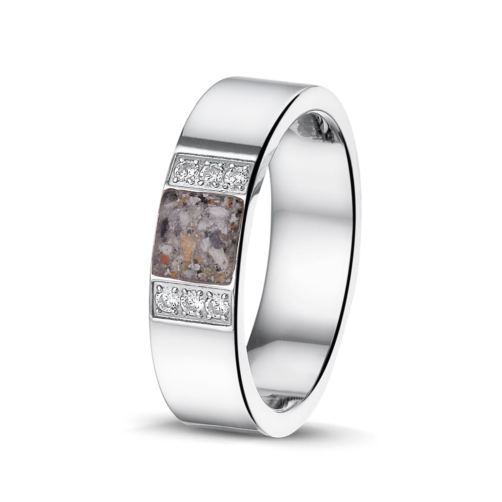 Ring als gedenksieraad 6 mm breed met een rechthoekig vlak aan de voorzijde, waar as of haar  in verwerkt wordt, aan beide zijden ingekleed door 6 stuks zirkonia's.