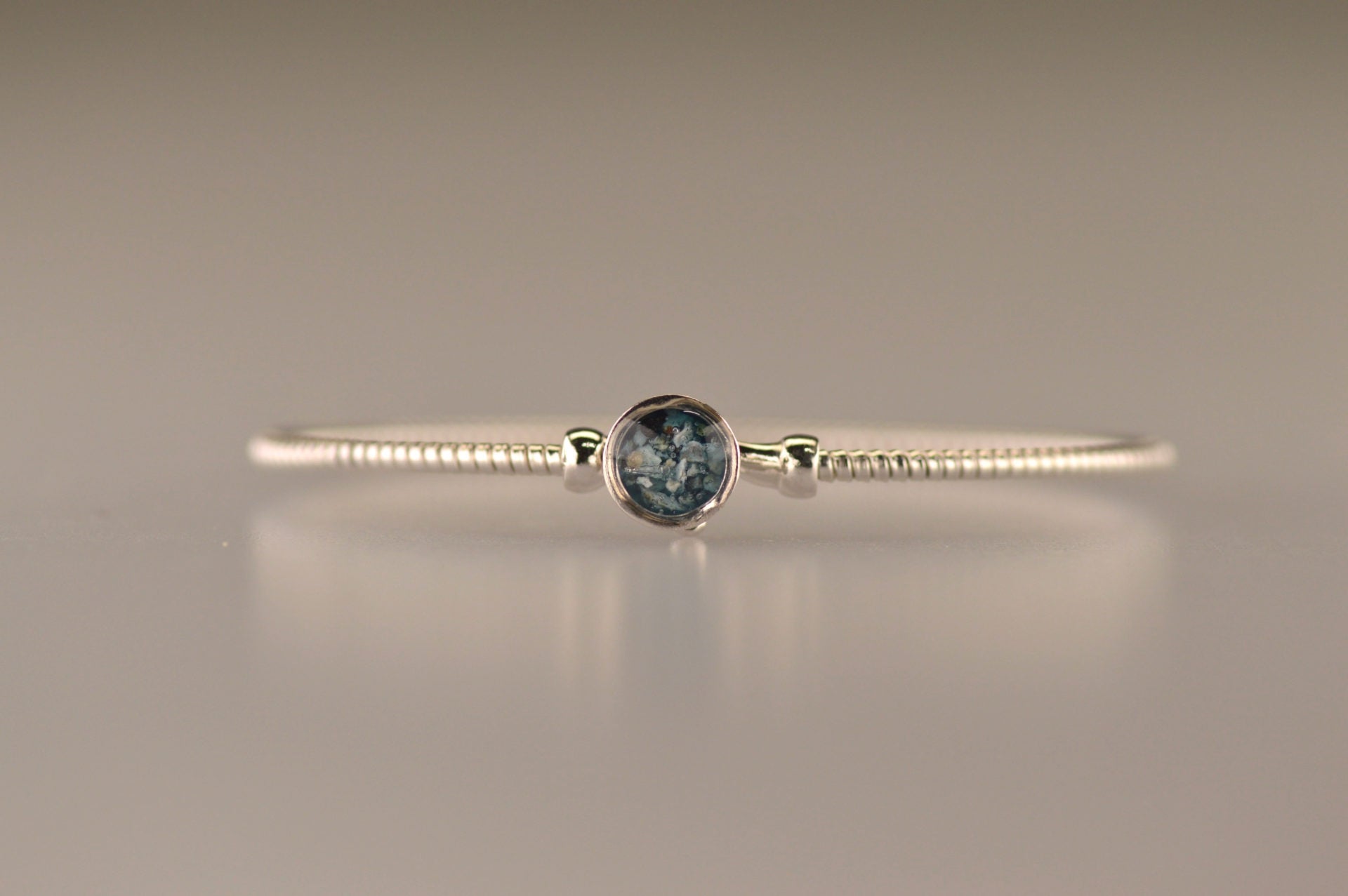 Zilveren as armband met in het midden een ornamentje, gedenksieraad, alle