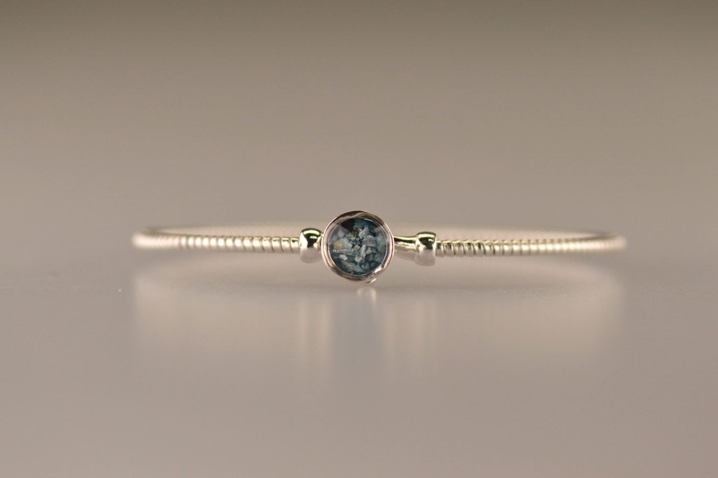 Zilveren as armband met in het midden een ornamentje, gedenksieraad, alle