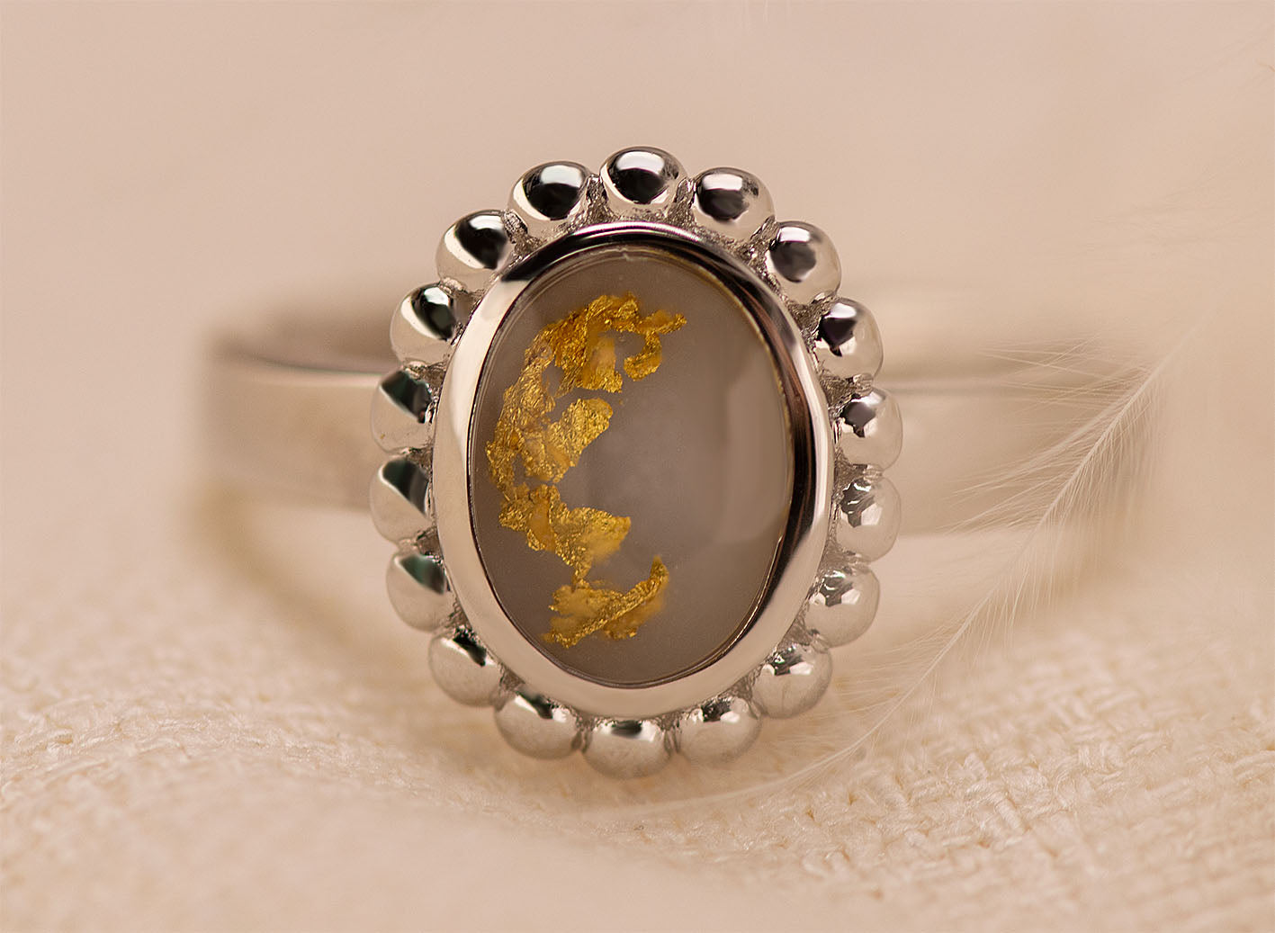 Gedenksieraad, asring 4 mm  waar aan de bovenzijde in druppelvorm met parelrand zichtbaar as of haar (of eventueel melktandjes of moedermelk) verwerkt wordt.  Alle