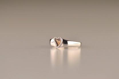 Gedenksieraad, gladde ring waar aan de bovenzijde zichtbaar as of haar verwerkt wordt in een hartje, rondom gezet met zirkonia's of diamanten naar keuze. Alle