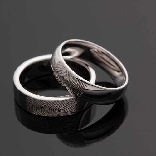 Deze asring van 6 mm breedte met vingerafdruk is heeft een subtiel weggewerkt askamertje, waar een symbolische hoeveelheid as of haar in kan bewaard worden. Alle