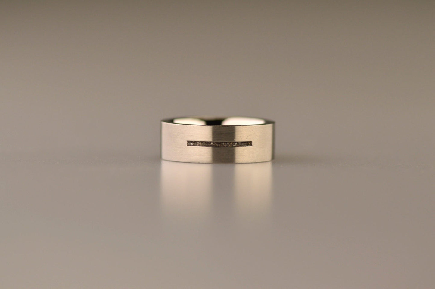 Ring als gedenksieraad 7 mm breed met één langwerpige streep waar as of haar  in verwerkt wordt.De asring is leverbaar in edelstaal, zilver en in 14 en 18 KT geelgoud/witgoud en roségoud. Alle