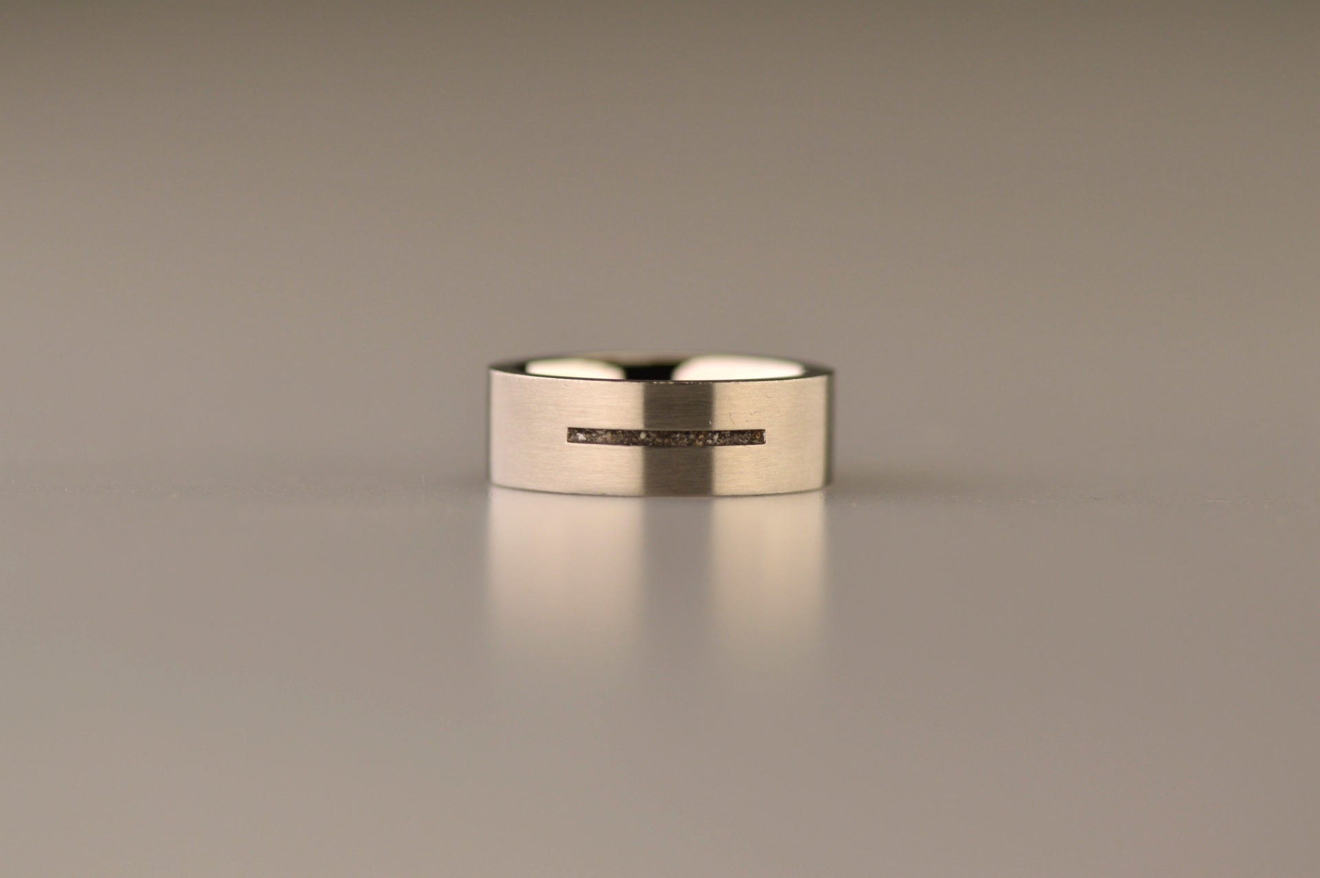 Ring als gedenksieraad 7 mm breed met één langwerpige streep waar as of haar  in verwerkt wordt.De asring is leverbaar in edelstaal, zilver en in 14 en 18 KT geelgoud/witgoud en roségoud. Alle