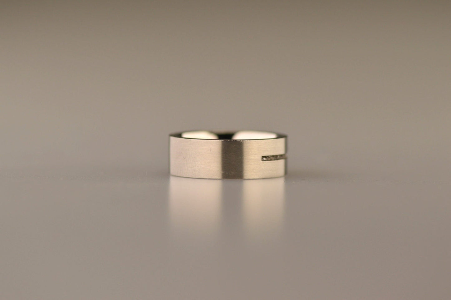 Ring als gedenksieraad 7 mm breed met één langwerpige streep waar as of haar  in verwerkt wordt.De asring is leverbaar in edelstaal, zilver en in 14 en 18 KT geelgoud/witgoud en roségoud. Alle