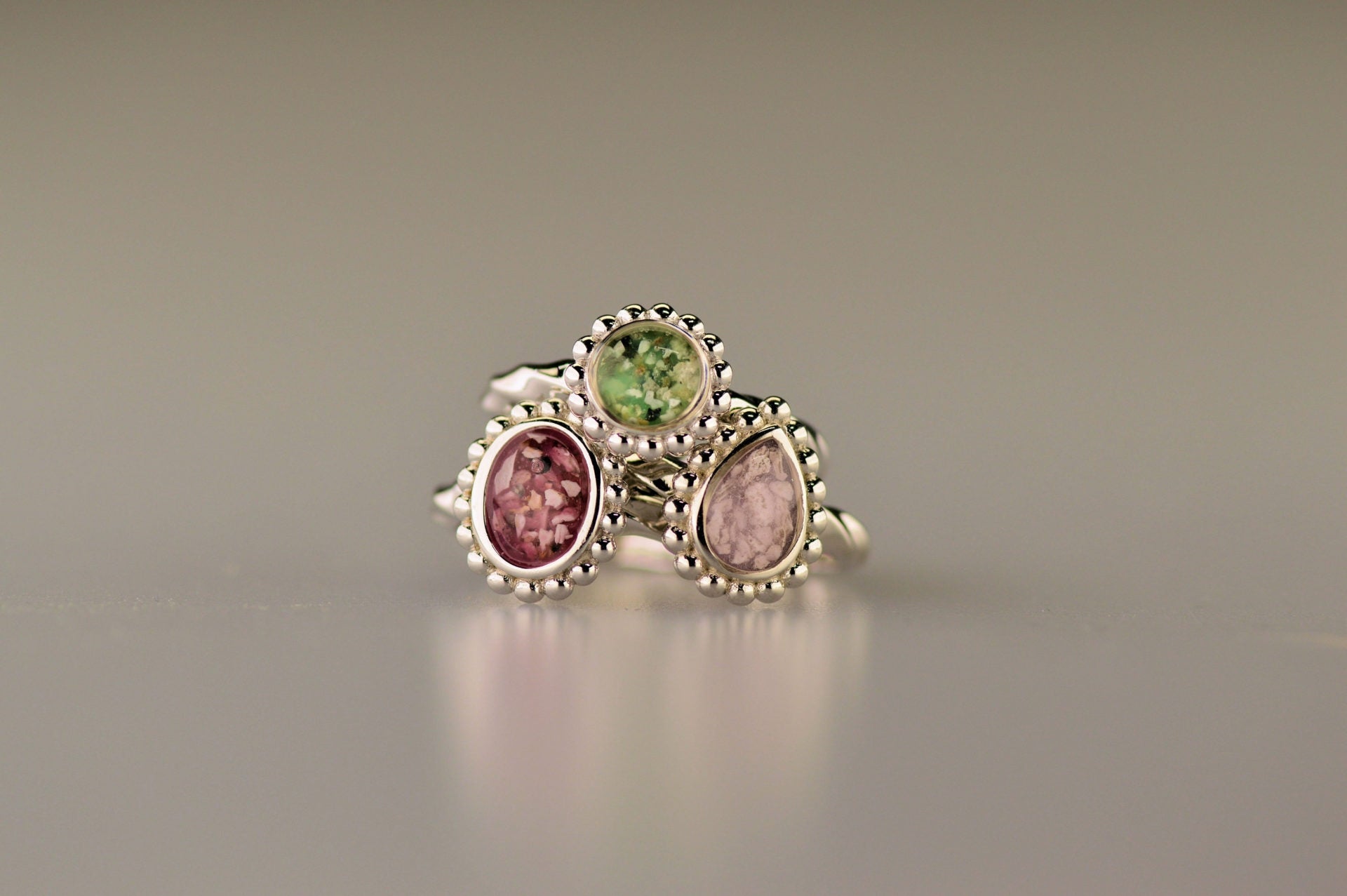 Gedenksieraad, asring met gedraaide scheen waar aan de bovenzijde in druppelvorm met parelrand zichtbaar as of haar (of eventueel melktandjes of moedermelk) verwerkt wordt.alle