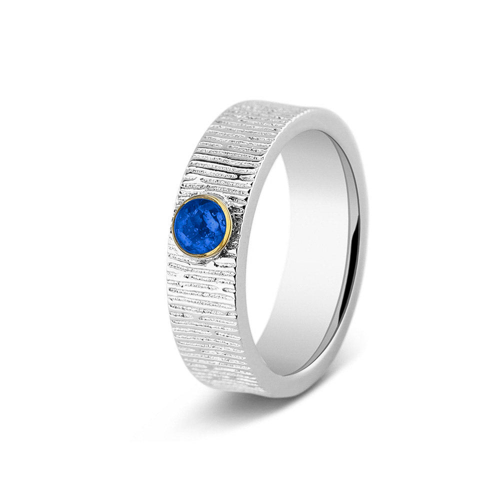 Ring 6 mm uit onze serie gedenksieraden, waar zichtbaar as of haar (of eventueel melktandjes of moedermelk) verwerkt wordt in het ronde ornamentje. Blue