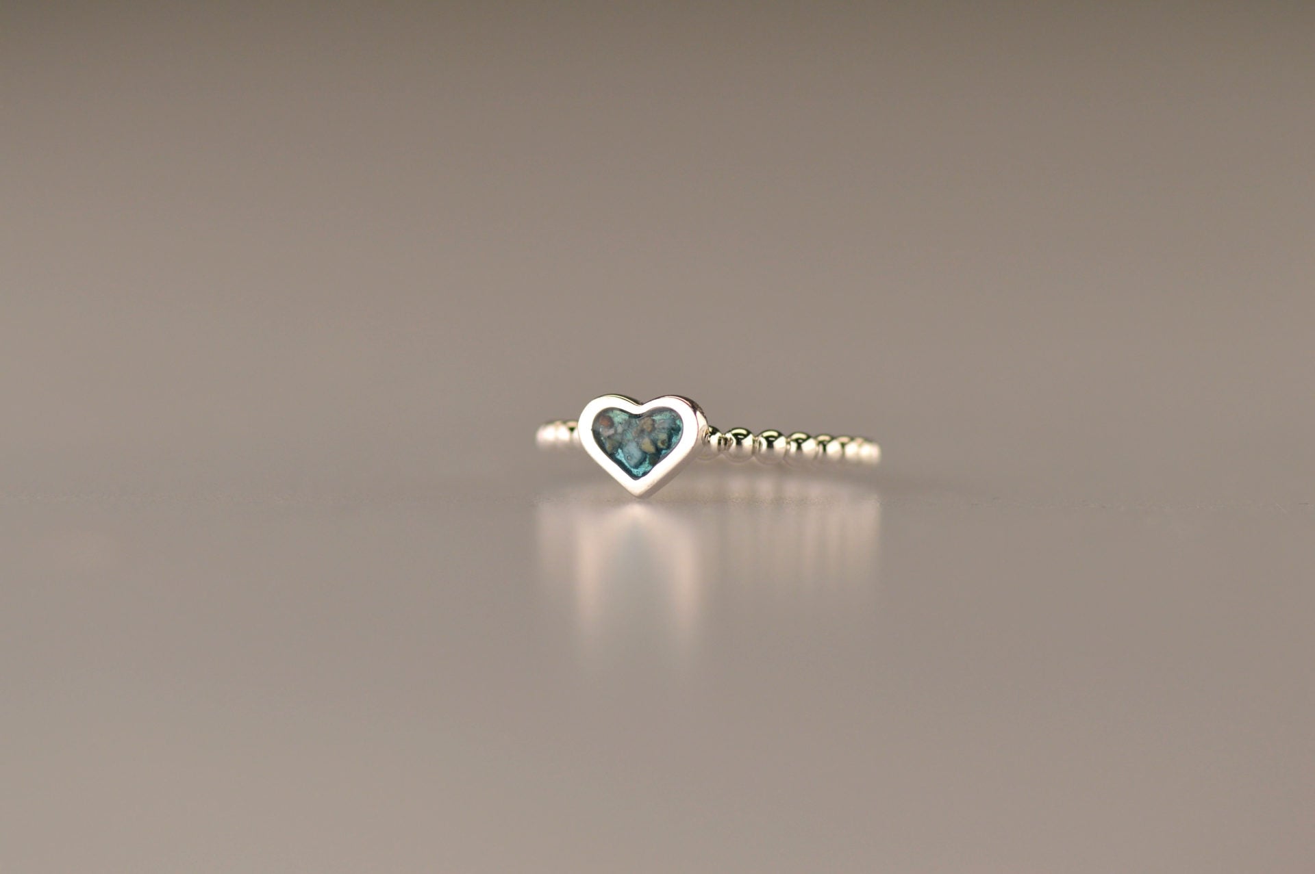 Bolletjes ring met een hartje er boven op , waar zichtbaar as of haar  in verwerkt wordt.De asring is leverbaar in zilver en in 14 en 18 KT geelgoud/witgoud en roségoud.