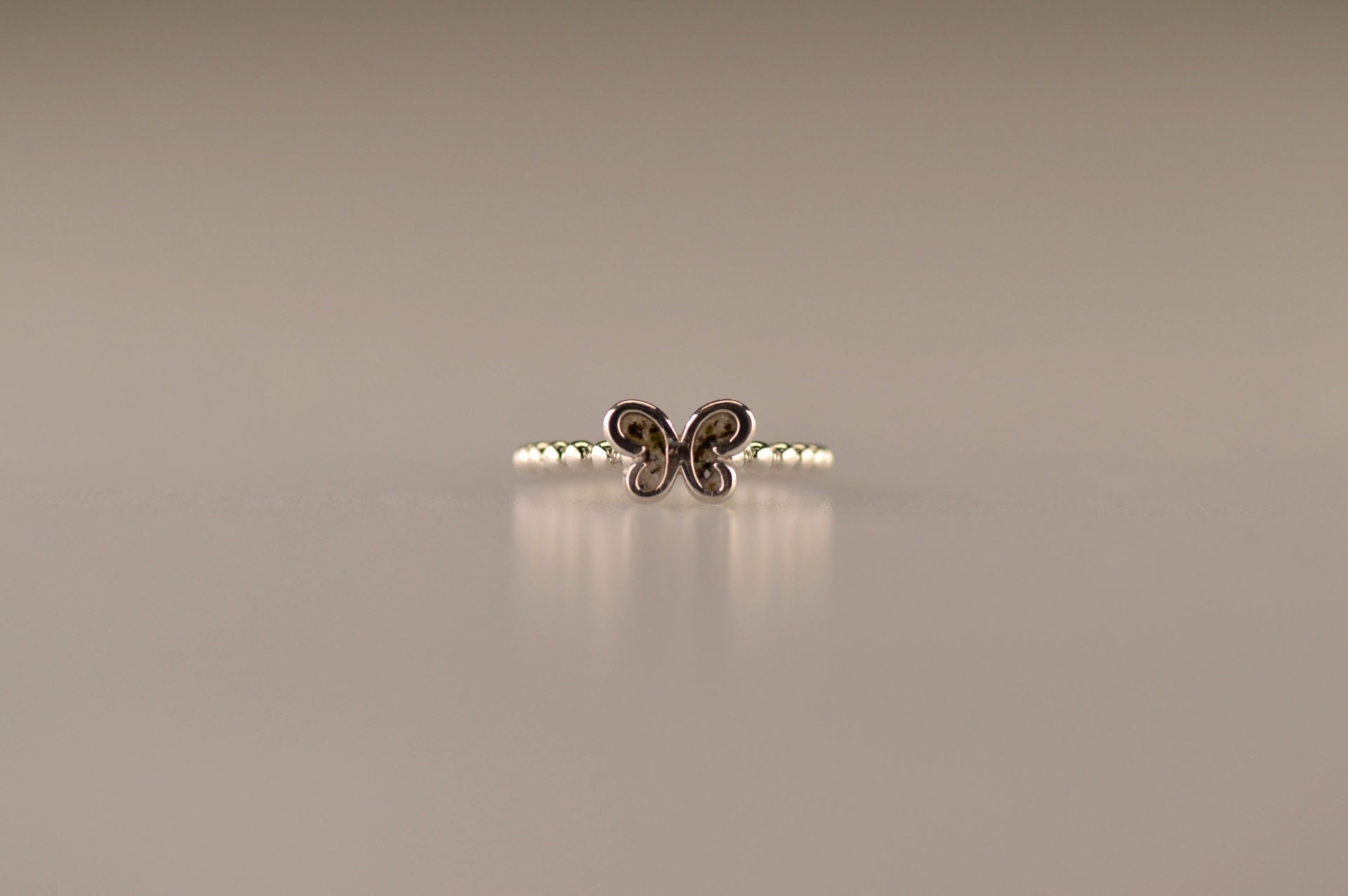 Afmeting vlinder: 8x6 mm, Ringband: 2 mm. Bolletjes ring als gedenksieraad met een vlinder er boven op , waar zichtbaar as of haar  in verwerkt wordt. alle