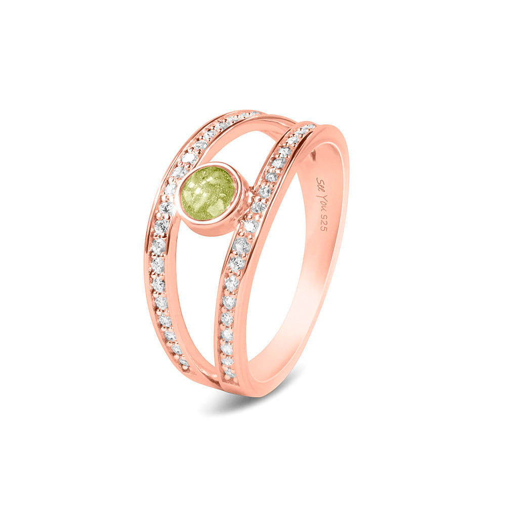 Gedenksieraad, ring waar aan de bovenzijde zichtbaar as of haar verwerkt wordt. In de bovenste helft van de ringband zijn subtiel edelstenen naar keuze gezet. Olive