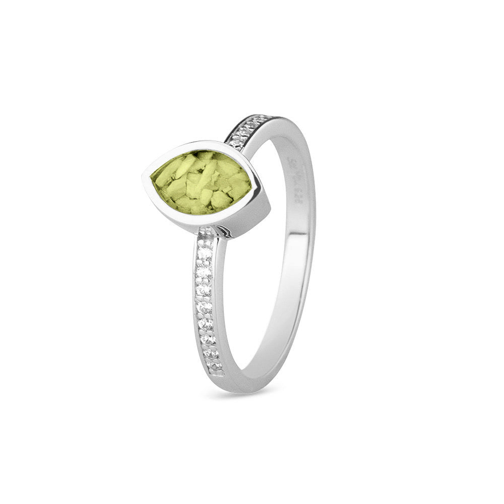 Gedenksieraad, ring 3 mm breed waar aan de bovenzijde zichtbaar as of haar verwerkt wordt. In de ringband zijn subtiel edelstenen naar keuze gezet. Olive