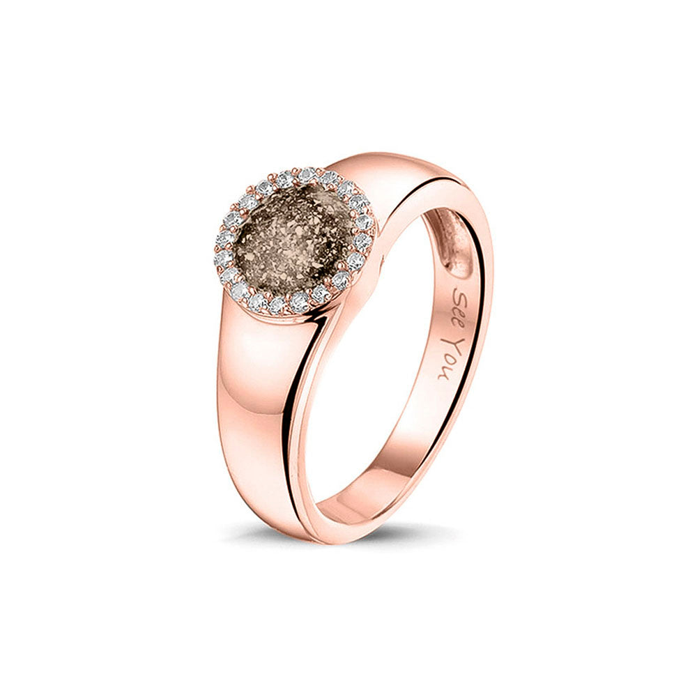 Gedenksieraad, gladde ring waar aan de bovenzijde zichtbaar as of haar verwerkt wordt in een rondje, rondom gezet met zirkonia's of diamanten naar keuze. Transparent
