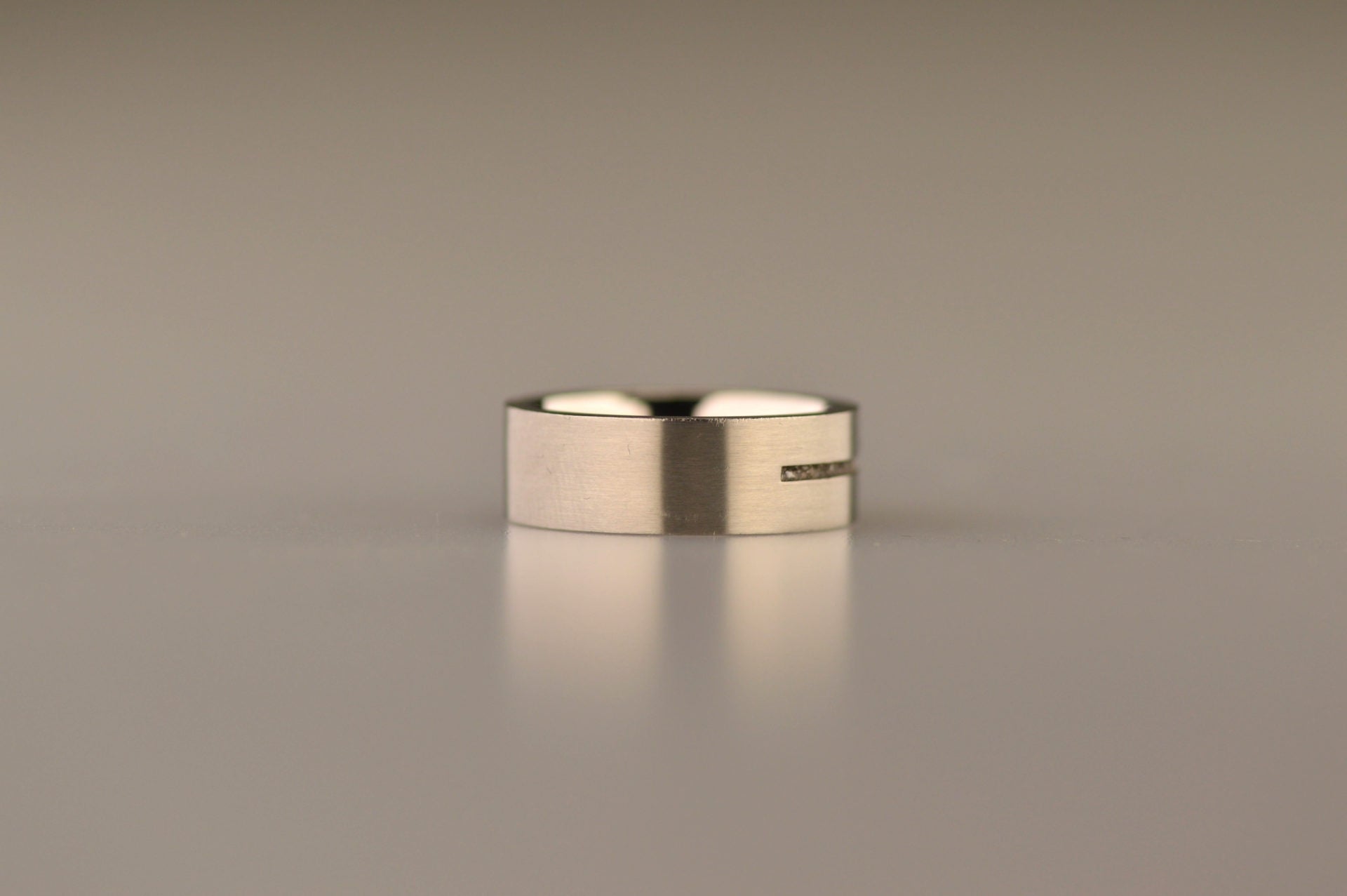 Ring als gedenksieraad 7 mm breed met één langwerpige streep waar as of haar  in verwerkt wordt.De asring is leverbaar in edelstaal, zilver en in 14 en 18 KT geelgoud/witgoud en roségoud. 